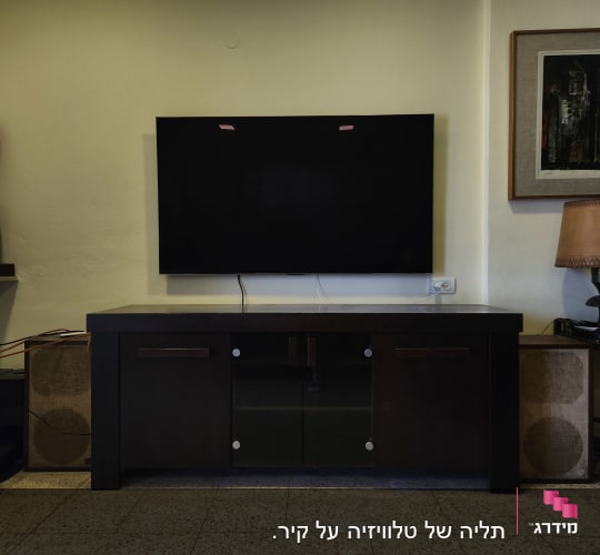 טלוויזיה תלויה על הקיר עם כבלים חשמליים